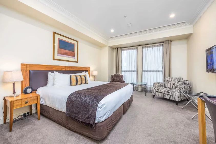 A king bed made up with white hotel linen in one of our studio apartments near Sky City